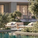 Sovereign Estates   Outdoor poolside seating area with beige loungers cushions and a wooden side table framed by greenery and a modern building 2026 Outdoor poolside seating area with beige loungers cushions and a wooden side table framed by greenery and a modern building