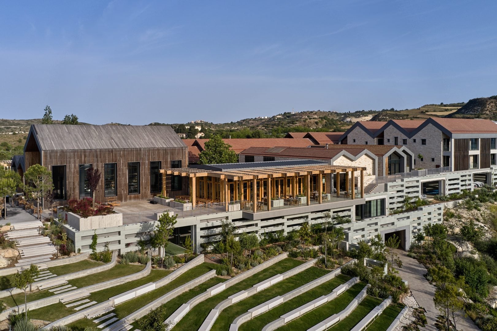 DJI_0478-1621x1080jpg - Sovereign Estates Sovereign Estates Aerial view of a hillside campus with tiered concrete terraces greenery and a long wooden pergola over a seating area 2026 Aerial view of a hillside campus with tiered concrete terraces greenery and a long wooden pergola over a seating area