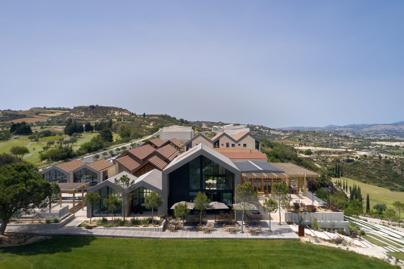 DJI_0648-1621x1080jpg - Sovereign Estates Sovereign Estates Modern resort building with angular roofs and glass façade outdoor seating on a terrace set on a hillside under a clear blue sky 2026 Modern resort building with angular roofs and glass façade outdoor seating on a terrace set on a hillside under a clear blue sky