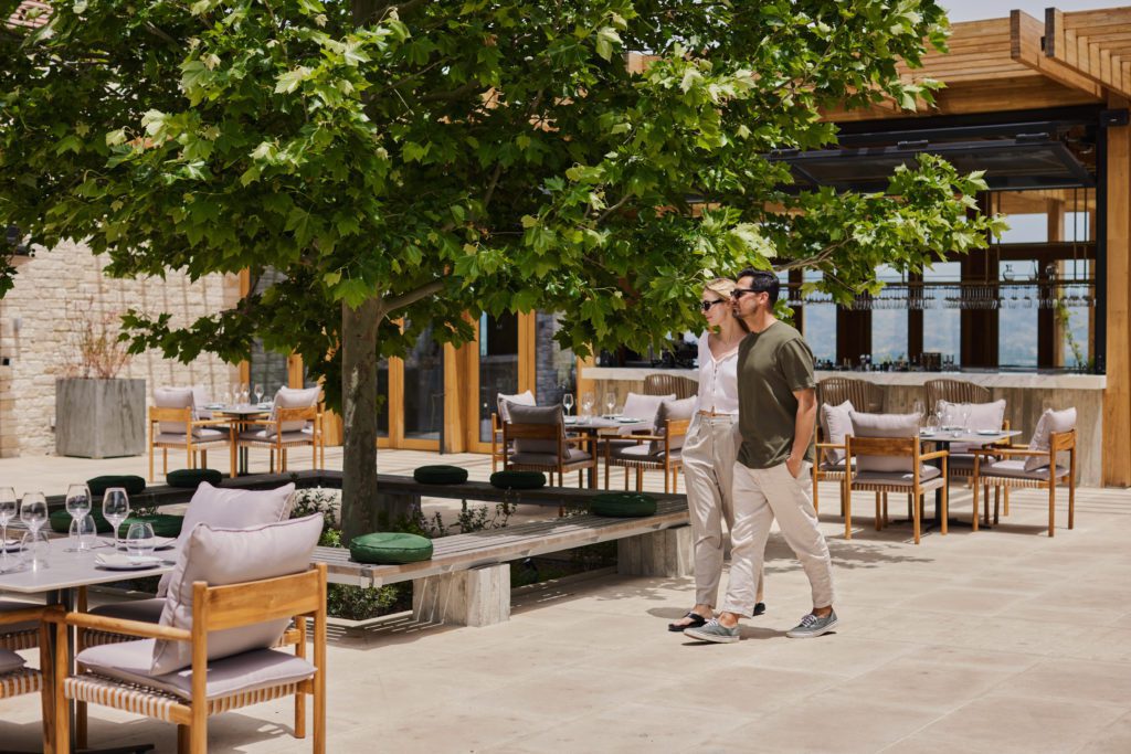 Square-1024x683jpg - Sovereign Estates Sovereign Estates Couple walking together through an outdoor restaurant patio with trees and white cushioned seating 2026 Couple walking together through an outdoor restaurant patio with trees and white cushioned seating