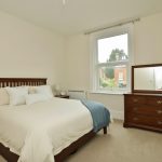 Sovereign Estates   Bright bedroom with a wooden bed white bedding and pillows and a blue throw at the foot of the bed a dresser with a mirror sits by a large window 2026 Bright bedroom with a wooden bed white bedding and pillows and a blue throw at the foot of the bed a dresser with a mirror sits by a large window