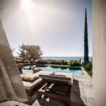 Sovereign Estates   Outdoor patio with cushioned lounge chairs by a rectangular pool overlooking the ocean on a sunny day 2026 Outdoor patio with cushioned lounge chairs by a rectangular pool overlooking the ocean on a sunny day