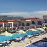 Sovereign Estates   Poolside view of a resort with blue lounge chairs and beige umbrellas peach colored buildings with red tiled roofs and distant hills 2026 Poolside view of a resort with blue lounge chairs and beige umbrellas peach colored buildings with red tiled roofs and distant hills