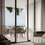 Sovereign Estates   Living room with floor to ceiling glass doors opening to a balcony wicker dining chairs around a wooden table with a distant sea view and greenery above 2026 Living room with floor to ceiling glass doors opening to a balcony wicker dining chairs around a wooden table with a distant sea view and greenery above