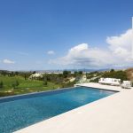 Sovereign Estates   Modern white contemporary house with a glass balcony beige pool deck and white outdoor seating overlooking a green golf course under a blue sky 2026 Modern white contemporary house with a glass balcony beige pool deck and white outdoor seating overlooking a green golf course under a blue sky