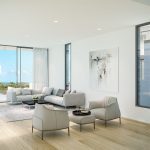 Sovereign Estates   Bright living room with large glass doors opening to a pool and ocean view modern gray sectional and seating area 2026 Bright living room with large glass doors opening to a pool and ocean view modern gray sectional and seating area