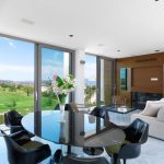 Sovereign Estates   Modern dining area with a glass oval table black chairs a floral centerpiece and floor to ceiling windows showing a golf course outside 2026 Modern dining area with a glass oval table black chairs a floral centerpiece and floor to ceiling windows showing a golf course outside