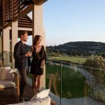 Sovereign Estates   Couple on a wooden terrace with drinks overlooking a green golf course at sunset with lounge seating nearby 2026 Couple on a wooden terrace with drinks overlooking a green golf course at sunset with lounge seating nearby
