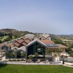 Sovereign Estates   Modern hillside resort with angular glass frontage brown tile roofs and an outdoor seating area on a stone patio overlooking green lawns and a valley 2026 Modern hillside resort with angular glass frontage brown tile roofs and an outdoor seating area on a stone patio overlooking green lawns and a valley