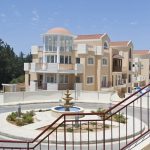 Sovereign Estates   Beige multi story apartment buildings surrounding a circular fountain in a landscaped roundabout with red railing in the foreground 2026 Beige multi story apartment buildings surrounding a circular fountain in a landscaped roundabout with red railing in the foreground