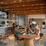 Sovereign Estates   Couple toasting wine glasses at a round wooden table in a modern openconcept restaurant 2026 Couple toasting wine glasses at a round wooden table in a modern openconcept restaurant