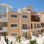 Sovereign Estates   Mediterraneanstyle apartment building with rounded glass tower multiple balconies and a pool area with blue lounge chairs nearby 2026 Mediterraneanstyle apartment building with rounded glass tower multiple balconies and a pool area with blue lounge chairs nearby