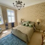 IMG_21_10_largejpg - Sovereign Estates Sovereign Estates Elegant bedroom with floral wallpaper chandelier and a teal upholstered bed flanked by two nightstands and lamps 2026 Elegant bedroom with floral wallpaper chandelier and a teal upholstered bed flanked by two nightstands and lamps