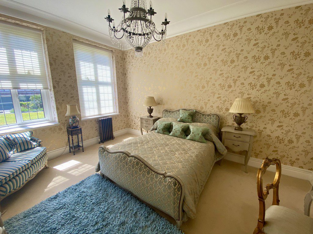 IMG_21_10_largejpg - Sovereign Estates Sovereign Estates Elegant bedroom with floral wallpaper chandelier and a teal upholstered bed flanked by two nightstands and lamps 2026 Elegant bedroom with floral wallpaper chandelier and a teal upholstered bed flanked by two nightstands and lamps