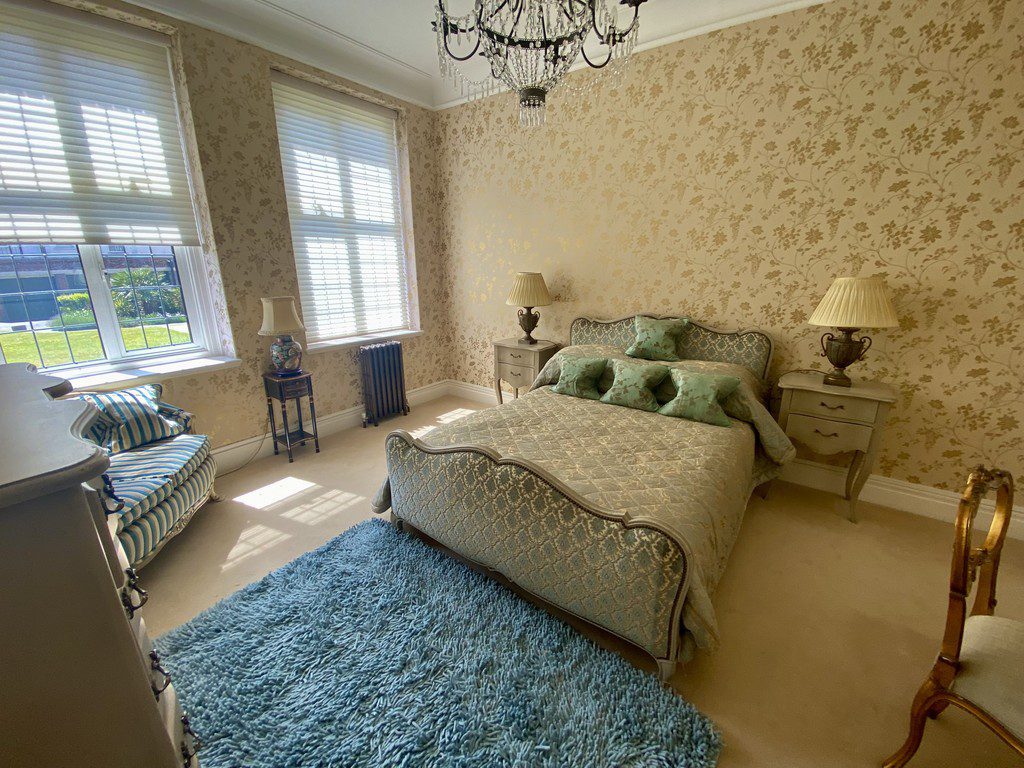 IMG_21_11_largejpg - Sovereign Estates Sovereign Estates Elegant bedroom with cream wallpaper ornate blue bed and wicker striped chairs under two large windows with blinds 2026 Elegant bedroom with cream wallpaper ornate blue bed and wicker striped chairs under two large windows with blinds
