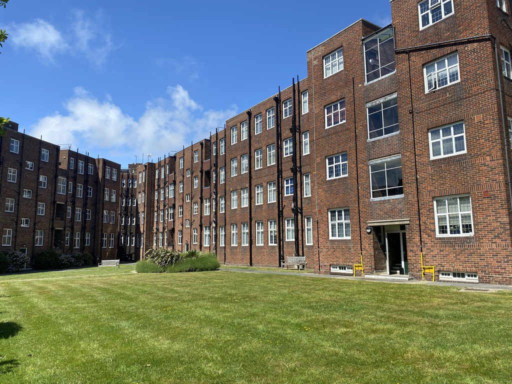 IMG_21_17_largejpg - Sovereign Estates Sovereign Estates Brick apartment buildings enclose a green lawn courtyard on a sunny day with a blue sky above 2026 Brick apartment buildings enclose a green lawn courtyard on a sunny day with a blue sky above