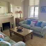 IMG_21_19_largejpg - Sovereign Estates Sovereign Estates Living room with two light blue patterned sofas colorful cushions a glass coffee table and a fireplace with a large mirror above 2026 Living room with two light blue patterned sofas colorful cushions a glass coffee table and a fireplace with a large mirror above
