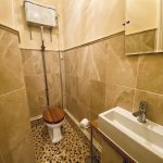 IMG_21_1_largejpg - Sovereign Estates Sovereign Estates Small beige tiled bathroom with a white toilet that has a wooden seat and a high mounted cistern with exposed pipes a white rectangular sink with a chrome faucet is adjacent and a wall cabinet mirror is visible above 2026 Small beige tiled bathroom with a white toilet that has a wooden seat and a high mounted cistern with exposed pipes a white rectangular sink with a chrome faucet is adjacent and a wall cabinet mirror is visible above