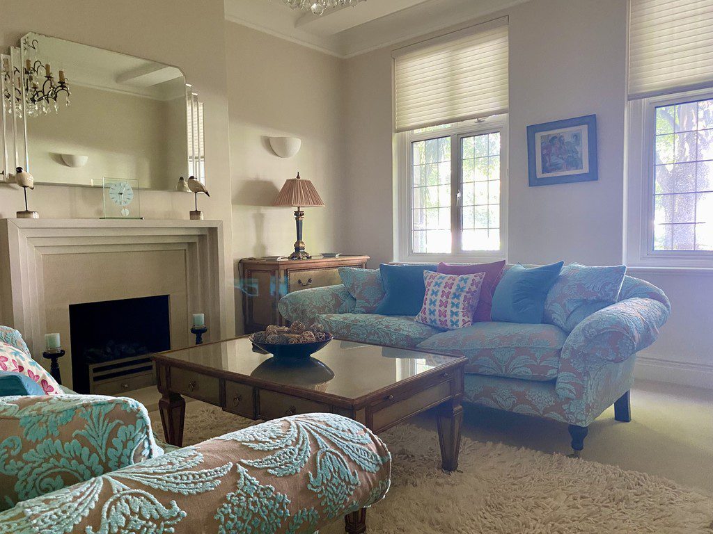 IMG_21_20_largejpg - Sovereign Estates Sovereign Estates A pastel blue living room with patterned sofa and matching chairs around a glass topped coffee table fireplace nearby and large windows letting in light 2026 A pastel blue living room with patterned sofa and matching chairs around a glass topped coffee table fireplace nearby and large windows letting in light