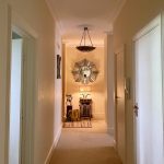 IMG_21_21_largejpg - Sovereign Estates Sovereign Estates Narrow beige hallway leading to a cozy entryway with a round sunburst mirror above a console table and lamp at the end of the hallNote remove bracket I'll rewrite properly 2026 Narrow beige hallway leading to a cozy entryway with a round sunburst mirror above a console table and lamp at the end of the hallNote remove bracket I'll rewrite properly