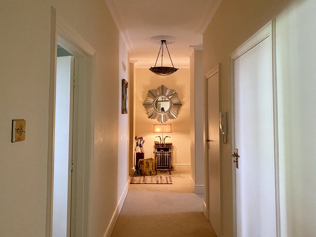 IMG_21_21_largejpg - Sovereign Estates Sovereign Estates Narrow beige hallway leading to a cozy entryway with a round sunburst mirror above a console table and lamp at the end of the hallNote remove bracket I'll rewrite properly 2026 Narrow beige hallway leading to a cozy entryway with a round sunburst mirror above a console table and lamp at the end of the hallNote remove bracket I'll rewrite properly