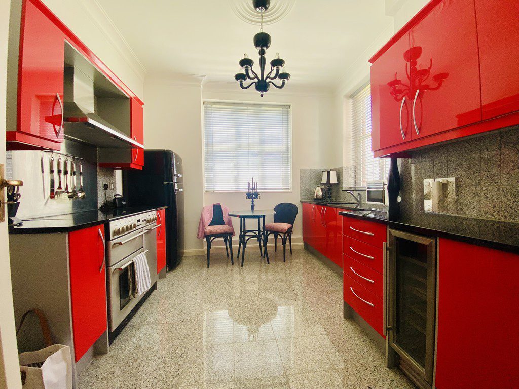 IMG_21_2_largejpg - Sovereign Estates Sovereign Estates Bright kitchen with glossy red cabinets stainless appliances and a small round dining table by a window 2026 Bright kitchen with glossy red cabinets stainless appliances and a small round dining table by a window
