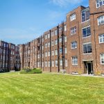 Sovereign Estates   Red brick apartment building surrounding a grassy courtyard under a blue sky many white framed windows and a few entrances with benches along the path 2026 Red brick apartment building surrounding a grassy courtyard under a blue sky many white framed windows and a few entrances with benches along the path