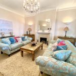 Sovereign Estates   Living room with two blue damask sofas a glass top coffee table and a beige shag rug beneath a chandelier 2026 Living room with two blue damask sofas a glass top coffee table and a beige shag rug beneath a chandelier