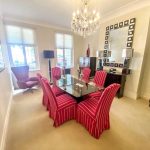 Sovereign Estates   Dining room with a glass top table surrounded by red striped chairs beneath a crystal chandelier 2026 Dining room with a glass top table surrounded by red striped chairs beneath a crystal chandelier
