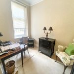 Sovereign Estates   Small home office with a wooden desk cluttered with papers a black desk lamp and a wicker wastebasket nearby 2026 Small home office with a wooden desk cluttered with papers a black desk lamp and a wicker wastebasket nearby