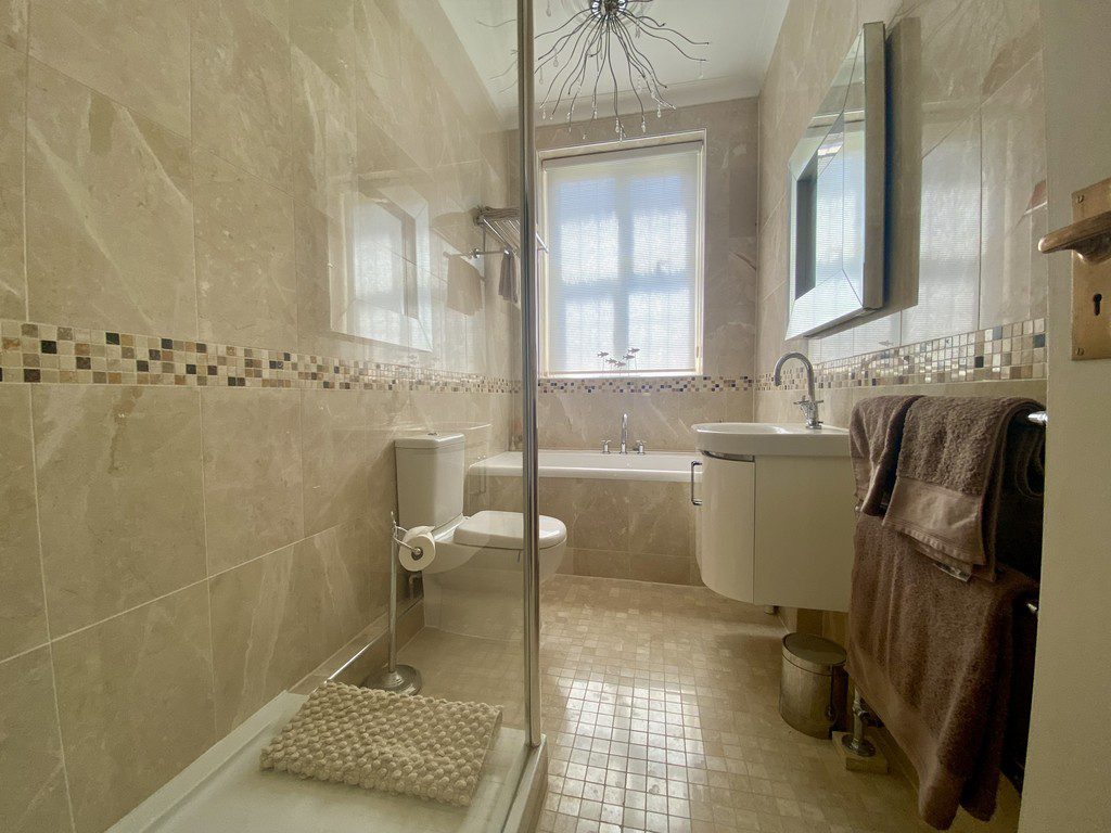 IMG_21_8_largejpg - Sovereign Estates Sovereign Estates Modern beige tiled bathroom with a glass shower enclosure toilet and a white vanity under a window 2026 Modern beige tiled bathroom with a glass shower enclosure toilet and a white vanity under a window