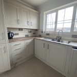 Sovereign Estates   L shaped kitchen with cream cabinets wood countertops and a double stainless steel sink under a large window kettle on the counter to the left 2026 L shaped kitchen with cream cabinets wood countertops and a double stainless steel sink under a large window kettle on the counter to the left