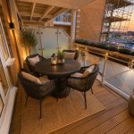 Sovereign Estates   Outdoor balcony at sunset with a round wicker table and five cushioned chairs a lantern centerpiece and potted trees overlooking a marina 2026 Outdoor balcony at sunset with a round wicker table and five cushioned chairs a lantern centerpiece and potted trees overlooking a marina