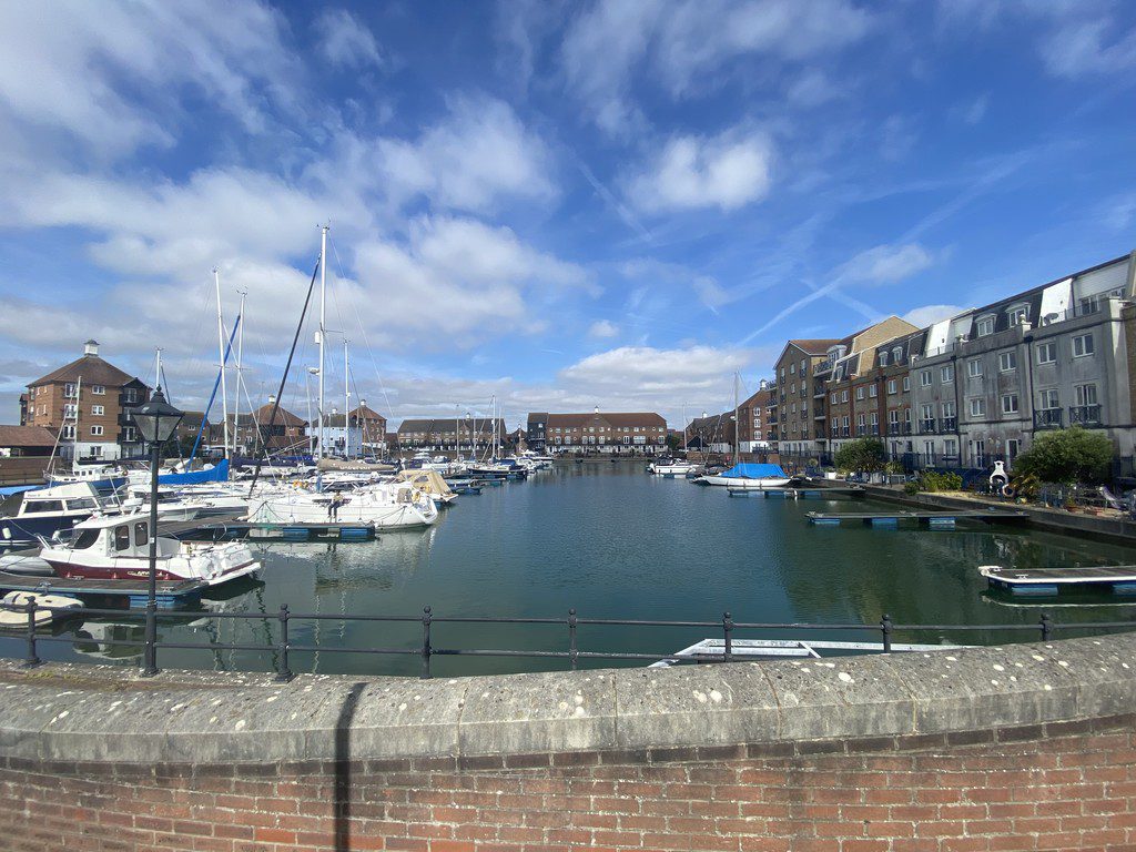 IMG_23_14_largejpg - Sovereign Estates Sovereign Estates Harbor filled with moored sailboats and yachts brick seawall in foreground and townhouses along the water under a blue sky 2026 Harbor filled with moored sailboats and yachts brick seawall in foreground and townhouses along the water under a blue sky