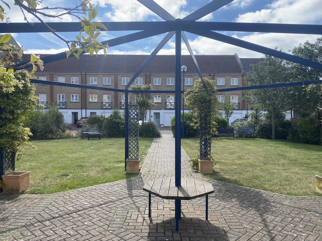 IMG_23_23_largejpg - Sovereign Estates Sovereign Estates Blue metal gazebo frame over a circular wooden table on a brick paved courtyard with benches and a grassy garden behind 2026 Blue metal gazebo frame over a circular wooden table on a brick paved courtyard with benches and a grassy garden behind