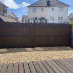 IMG_23_30_largejpg - Sovereign Estates Sovereign Estates Backyard with a tall dark wooden fence a pebble ground and a wooden deck in the foreground under a sunny sky 2026 Backyard with a tall dark wooden fence a pebble ground and a wooden deck in the foreground under a sunny sky