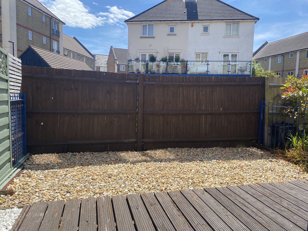 IMG_23_30_largejpg - Sovereign Estates Sovereign Estates Backyard with a tall dark wooden fence a pebble ground and a wooden deck in the foreground under a sunny sky 2026 Backyard with a tall dark wooden fence a pebble ground and a wooden deck in the foreground under a sunny sky