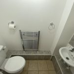 IMG_23_36_largejpg - Sovereign Estates Sovereign Estates Small bathroom with a wall mounted polished metal towel rail toilet and sink in a compact space with tiled floor and partial tiled wall Functional note contains a toilet sink and towel rail used as a basic restroom 2026 Small bathroom with a wall mounted polished metal towel rail toilet and sink in a compact space with tiled floor and partial tiled wall Functional note contains a toilet sink and towel rail used as a basic restroom