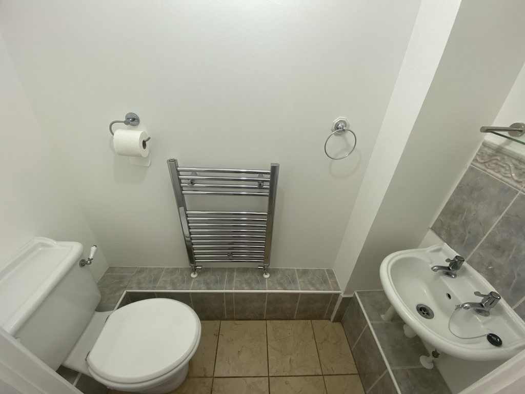 IMG_23_36_largejpg - Sovereign Estates Sovereign Estates Small bathroom with a wall mounted polished metal towel rail toilet and sink in a compact space with tiled floor and partial tiled wall Functional note contains a toilet sink and towel rail used as a basic restroom 2026 Small bathroom with a wall mounted polished metal towel rail toilet and sink in a compact space with tiled floor and partial tiled wall Functional note contains a toilet sink and towel rail used as a basic restroom