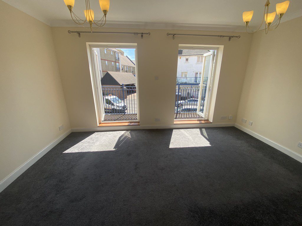 IMG_23_40_largejpg - Sovereign Estates Sovereign Estates Empty living room with gray carpet and cream walls featuring two tall open doorswindows that lead to a small balcony and let in sunlight 2026 Empty living room with gray carpet and cream walls featuring two tall open doorswindows that lead to a small balcony and let in sunlight