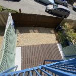 IMG_23_51_largejpg - Sovereign Estates Sovereign Estates Bird's eye view of a small gravel yard enclosed by wooden fences with a wooden deck and blue railing stairs from above 2026 Bird's eye view of a small gravel yard enclosed by wooden fences with a wooden deck and blue railing stairs from above