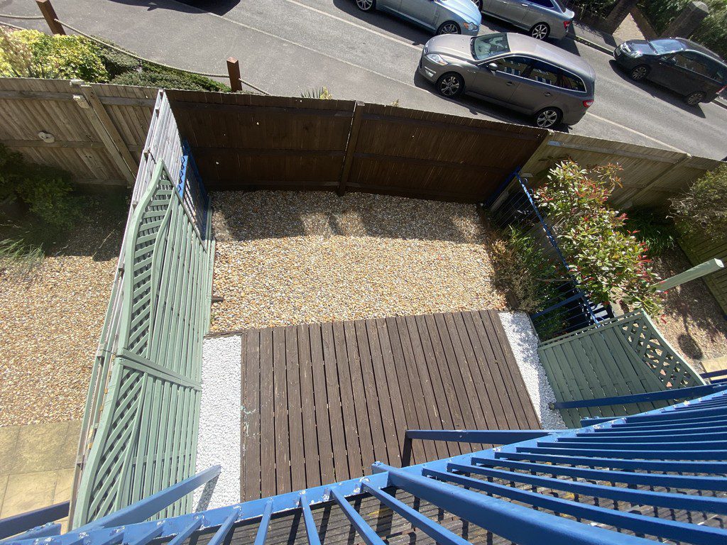 IMG_23_51_largejpg - Sovereign Estates Sovereign Estates Bird's eye view of a small gravel yard enclosed by wooden fences with a wooden deck and blue railing stairs from above 2026 Bird's eye view of a small gravel yard enclosed by wooden fences with a wooden deck and blue railing stairs from above