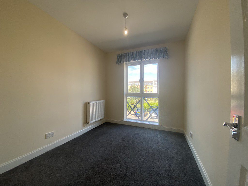 IMG_23_56_largejpg - Sovereign Estates Sovereign Estates Small empty room with cream walls dark carpet and a radiator along the left wall a large window with a balcony railing lets in daylight showing buildings outside 2026 Small empty room with cream walls dark carpet and a radiator along the left wall a large window with a balcony railing lets in daylight showing buildings outside