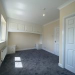 IMG_23_65_largejpg - Sovereign Estates Sovereign Estates Bright empty bedroom with built in white cupboards above a desk alcove beige walls and gray carpet window and radiator on the left 2026 Bright empty bedroom with built in white cupboards above a desk alcove beige walls and gray carpet window and radiator on the left