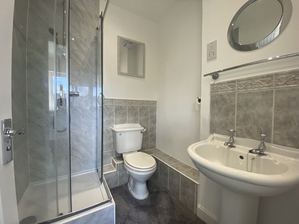 IMG_23_71_largejpg - Sovereign Estates Sovereign Estates Compact bathroom with a glass front shower toilet and pedestal sink against white and gray tiled walls 2026 Compact bathroom with a glass front shower toilet and pedestal sink against white and gray tiled walls