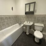 IMG_23_76_largejpg - Sovereign Estates Sovereign Estates Bathroom with white bathtub pedestal sink and toilet along tiled walls a gray wall cabinet above and a feather decal on the wall 2026 Bathroom with white bathtub pedestal sink and toilet along tiled walls a gray wall cabinet above and a feather decal on the wall