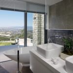 Sovereign Estates   Modern bathroom with a freestanding tub and dual sinks large glass doors offering a scenic hillside view outside 2026 Modern bathroom with a freestanding tub and dual sinks large glass doors offering a scenic hillside view outside