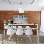 Sovereign Estates   Bright modern kitchen with warm wood cabinetry island and glass dining table with white chairs 2026 Bright modern kitchen with warm wood cabinetry island and glass dining table with white chairs