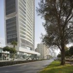 Sovereign Estates   Tall curved modern building with glass storefronts lining a street palm trees and a park on the right a jogger runs along the sidewalk 2026 Tall curved modern building with glass storefronts lining a street palm trees and a park on the right a jogger runs along the sidewalk