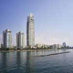 Sovereign Estates   Tall modern skyscraper with a curved top along a waterfront flanked by glass high rises and a calm harbor 2026 Tall modern skyscraper with a curved top along a waterfront flanked by glass high rises and a calm harbor